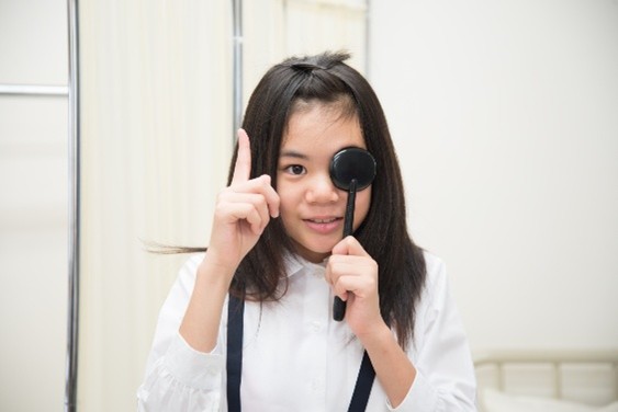 視力検査で片目を隠して測定している子供